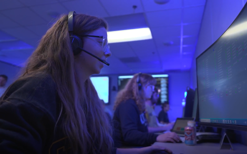 A woman using a computer to participate in a wargame.
